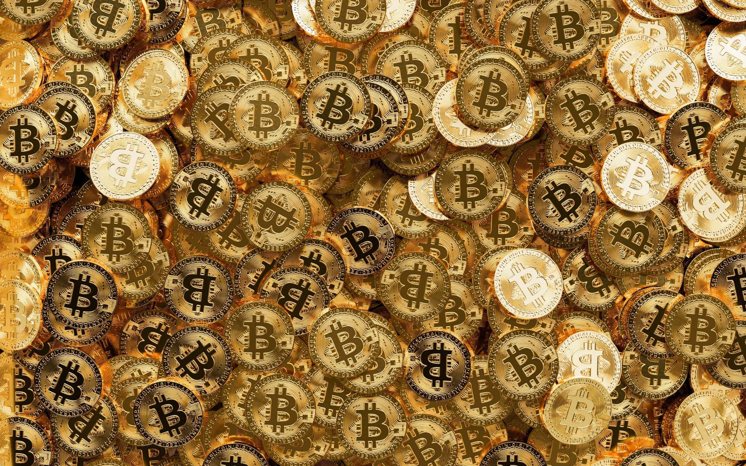 Ein Stapel glänzender goldfarbener Münzen, jede mit dem ikonischen Bitcoin-Symbol verziert, bedeckt das gesamte Bild.