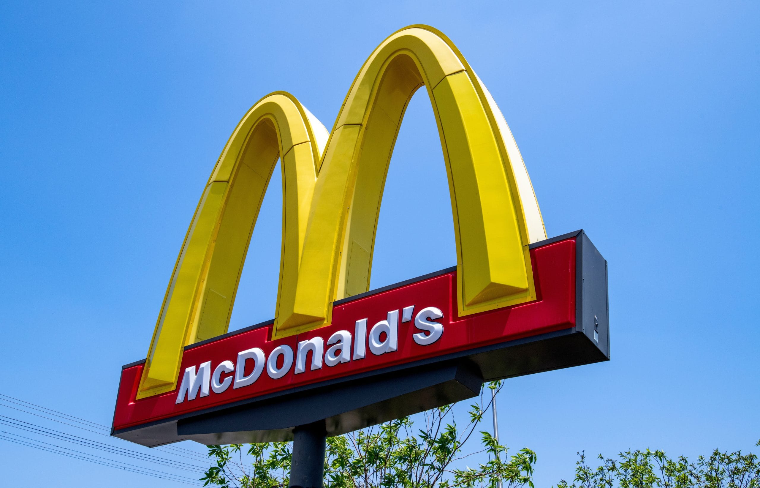 Das Bild zeigt ein McDonald's-Schild mit seinen charakteristischen gelben Bögen, die sich deutlich vor einem klaren blauen Himmel abheben.