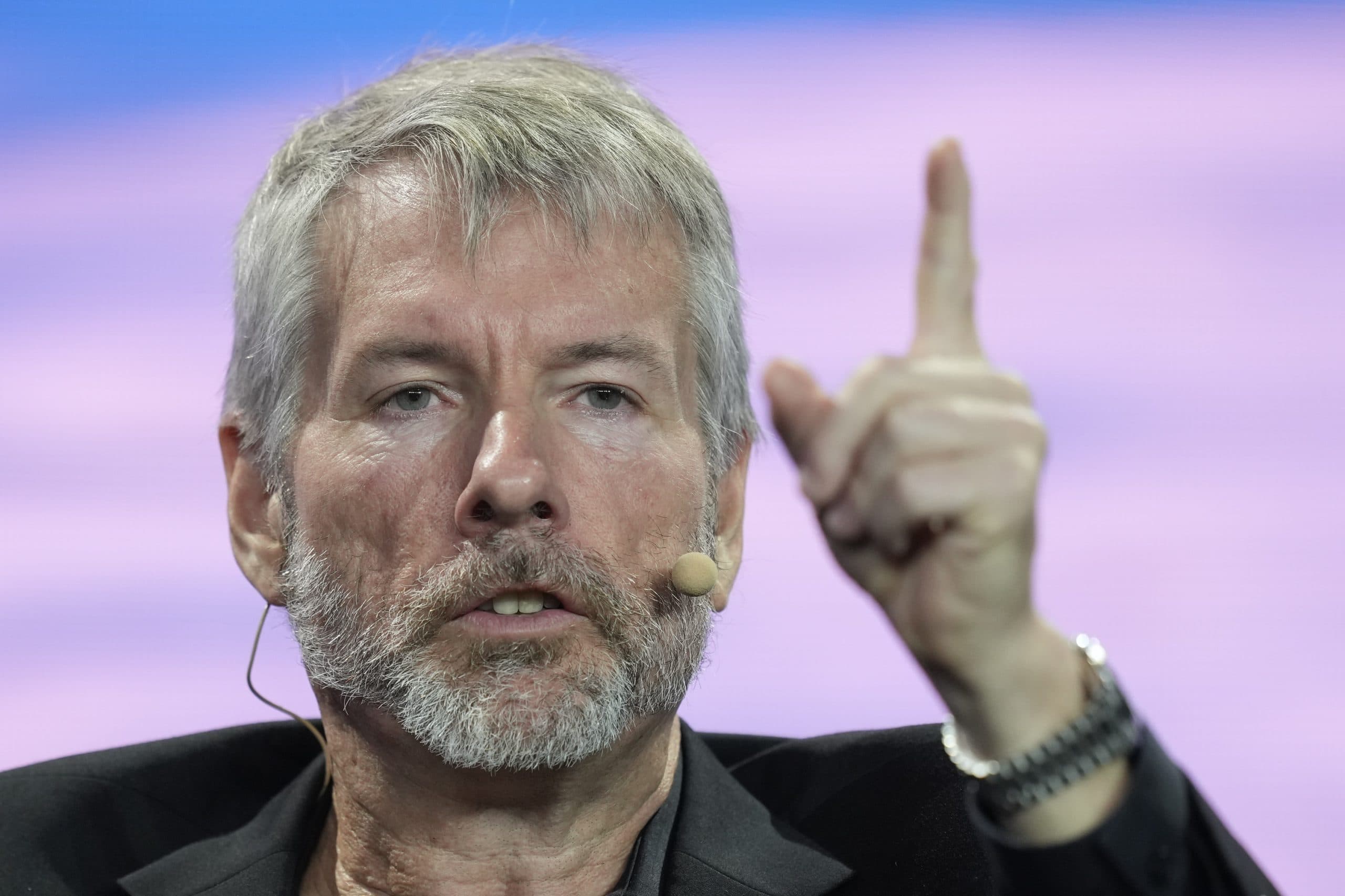 Michael Saylor gestikuliert mit einem erhobenen Finger, als würde er die Feinheiten von Bitcoin erklären, und zugleich vor XRP und Ripple warnen