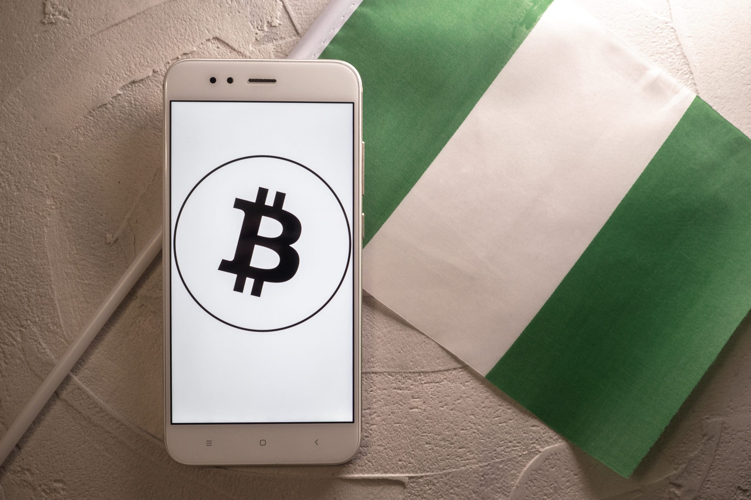 Bitcoin auf Handy neben Nigeria-Flagge