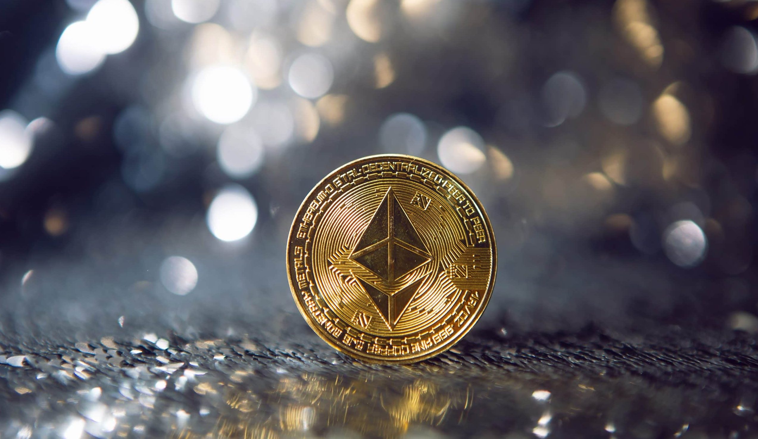 Eine glänzende Ethereum-Goldmünze steht elegant auf einer reflektierenden Oberfläche, ihr Glanz wird durch die verschwommenen Lichter, die im Hintergrund schimmern, verstärkt.