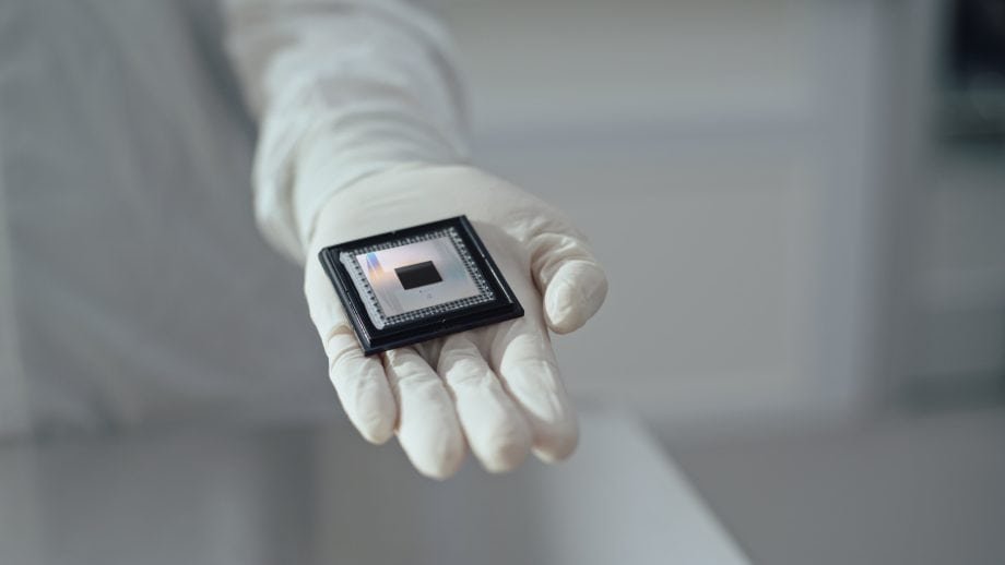 Eine behandschuhte Hand hält einen Computer-Mikrochip, der für das Bitcoin-Mining unerlässlich ist, in einer sauberen, sterilen Umgebung.