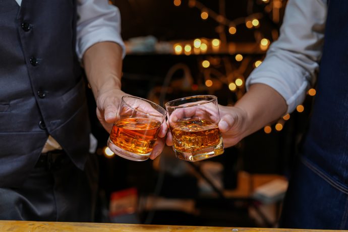 Zwei Männer stoßen mit Whiskey an als Symbol für die Feier des Bitcoin-Einstieges