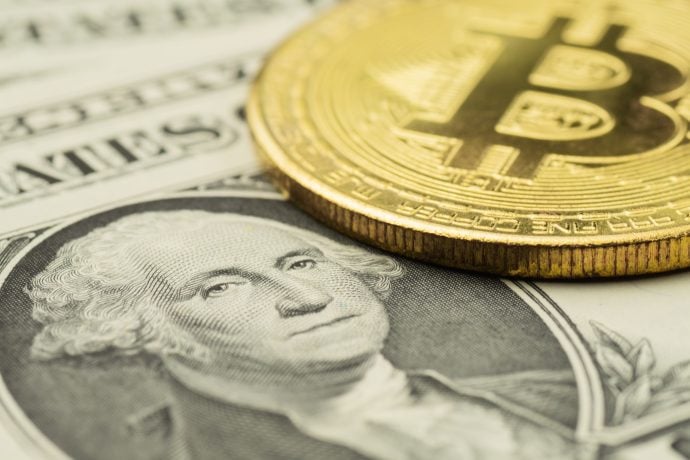 Eine Nahaufnahme eines schimmernden goldenen Bitcoins schmiegt sich an einen US-Ein-Dollar-Schein und ergänzt das ikonische Porträt von George Washington perfekt.