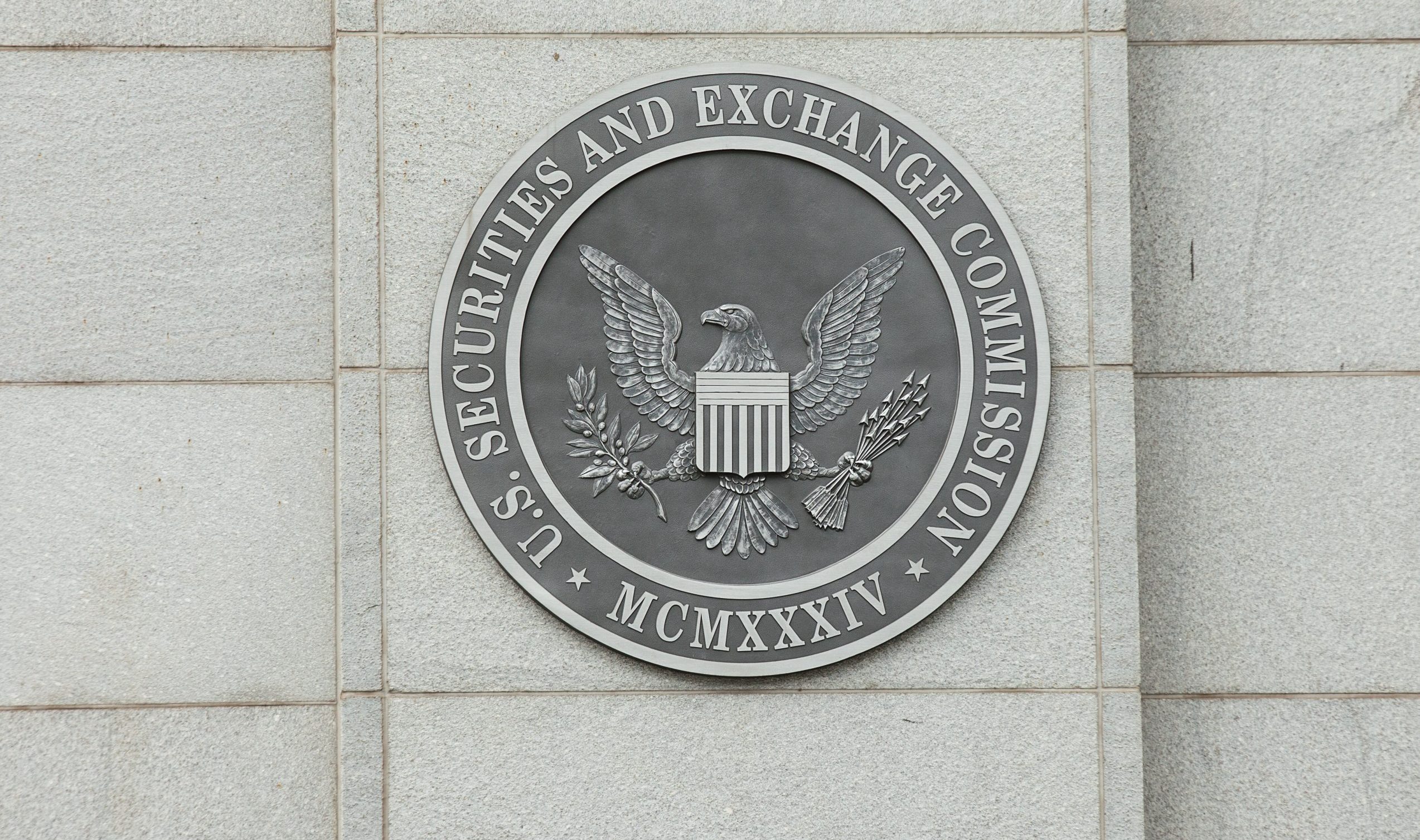 Das Siegel der US-Börsenaufsichtsbehörde (Securities and Exchange Commission) prangt stolz auf einer Steinmauer und zeigt einen Adler mit Schild, Olivenzweig und Pfeilen. Die im Jahr MCMXXXIV (1934) gegründete Behörde überwacht heute sich entwickelnde Märkte, darunter auch Krypto-Vermögenswerte.