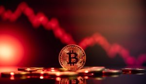 Eine Bitcoin-Münze liegt auf einer reflektierenden Oberfläche, im Hintergrund zeichnet sich ein rotes, nach unten gerichtetes Liniendiagramm ab, das einen kürzlichen Rückgang des Wertes der Kryptowährung signalisiert.