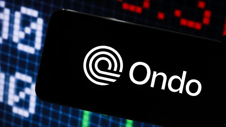 Auf einem Smartphone-Bildschirm ist das Ondo-Logo deutlich zu sehen. Im Hintergrund findet sich ein Börsendiagramm.