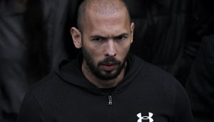 Ein Mann mit Bart und einem schwarzen Kapuzenpullover von Under Armour blickt nach vorne und verkörpert das Selbstvertrauen von Andrew Tate.