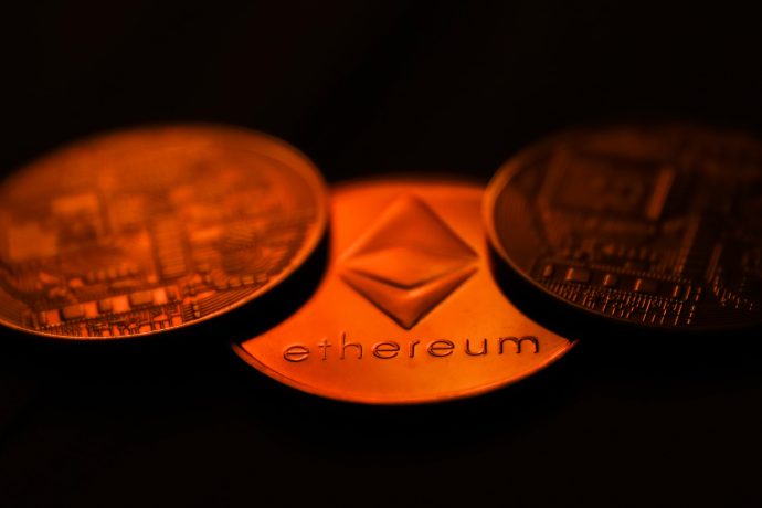 Im Mittelpunkt stehen drei glänzende Ethereum-Goldmünzen, die das Wort „Ethereum“ und sein unverwechselbares Symbol zeigen.