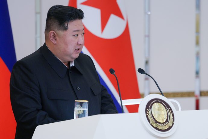 Kim Jong-un im dunklen Anzug spricht an einem Podium mit einer nordkoreanischen Flagge im Hintergrund und deutet damit mögliche Wirtschaftsgespräche an, die an El Salvadors Pionierarbeit im Umgang mit Bitcoin erinnern.