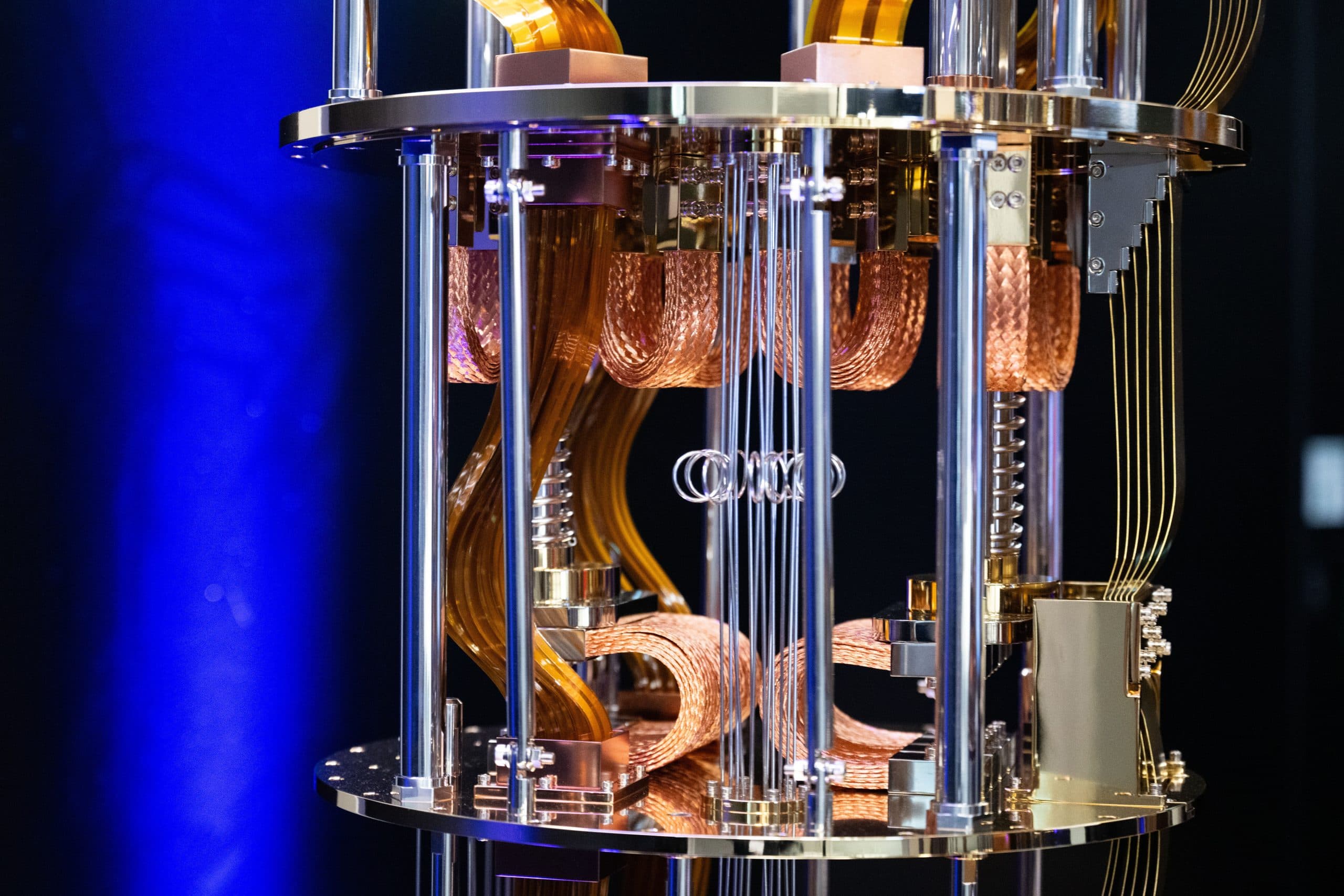 Eine Nahaufnahme des Kryostaten eines Quantencomputers zeigt schimmernde Kupfer- und Goldkomponenten, die aufwendig verdrahtet und strukturiert sind und sich vom dunklen Hintergrund abheben.