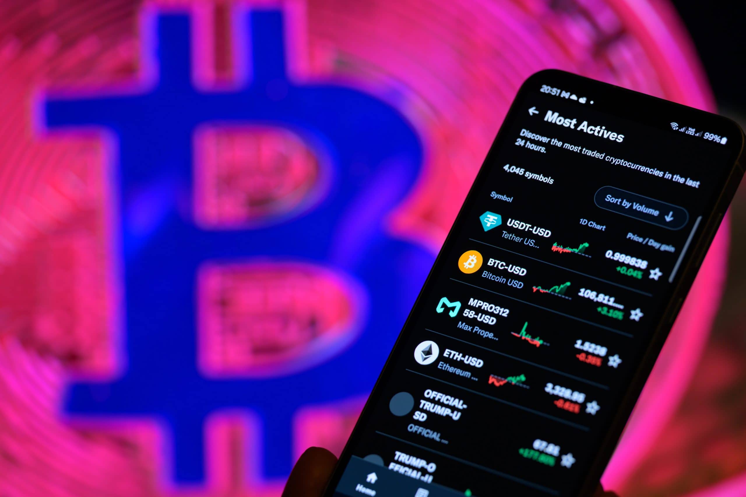 Auf einem Smartphone werden Handelsdaten zu Kryptowährungen angezeigt. Im Hintergrund ist ein buntes, verschwommenes Bitcoin-Logo zu sehen – ein unverzichtbares Tool für die Verwaltung von Bitcoin-Portfolios, selbst bei einem Minus von 23 Prozent.