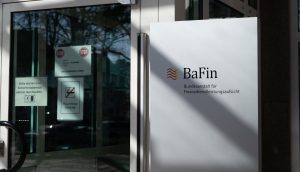 Eingang zum BaFin-Büro mit Glastür, Schild mit der Aufschrift „Bundesanstalt für Finanzdienstleistungsaufsicht“ und Warnhinweisen.