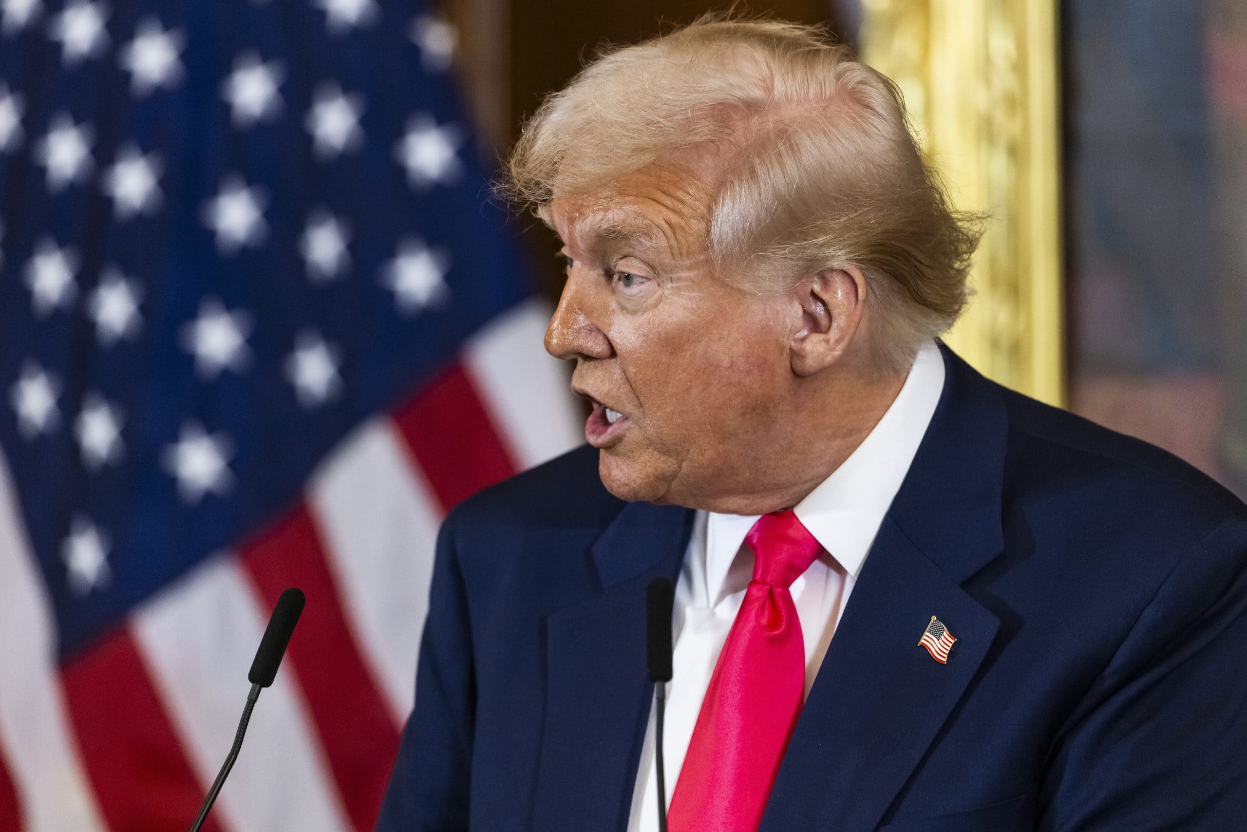 US Supreme Court kippt Trump-Zölle Bitcoin: Donald Trump spricht vor US-Flagge am Rednerpult