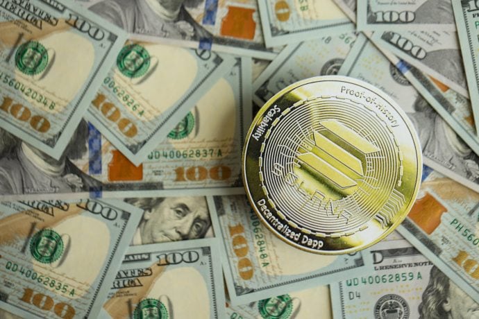 Eine Solana-Münze wird auf verstreute 100-Dollar-Scheine gelegt, was auf subtile Weise ihren Aufstieg widerspiegelt, während sie den breiteren Stablecoin-Markt erobert.