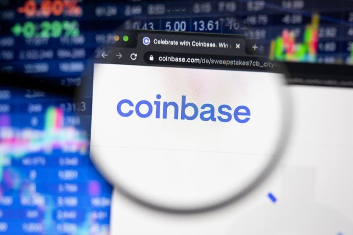Eine Lupe schwebt über dem Coinbase-Logo und enthüllt dessen Details vor einem verschwommenen Hintergrund aus Börsendaten und Diagrammen. Dies unterstreicht die zentrale Rolle von Coinbase in der digitalen Finanzlandschaft.