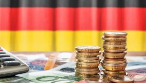 Stapel von Euromünzen und -scheinen liegen neben einem Taschenrechner, mit einem Hauch digitaler Zahlen, die auf Kryptoberechnungen hindeuten, und das alles vor dem Hintergrund der deutschen Flagge.