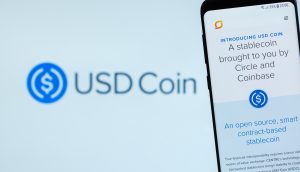 Smartphone, auf dem die USD Coin-Webseite vor einem unscharfen Hintergrund mit dem USD Coin-Logo angezeigt wird.