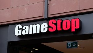 GameStop-Ladenschild mit fettgedruckter weißer und roter Schrift auf dunklem Hintergrund über dem Eingang.