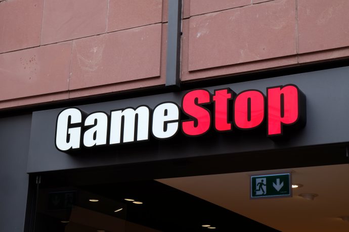 GameStop-Ladenschild mit fettgedruckter weißer und roter Schrift auf dunklem Hintergrund über dem Eingang.