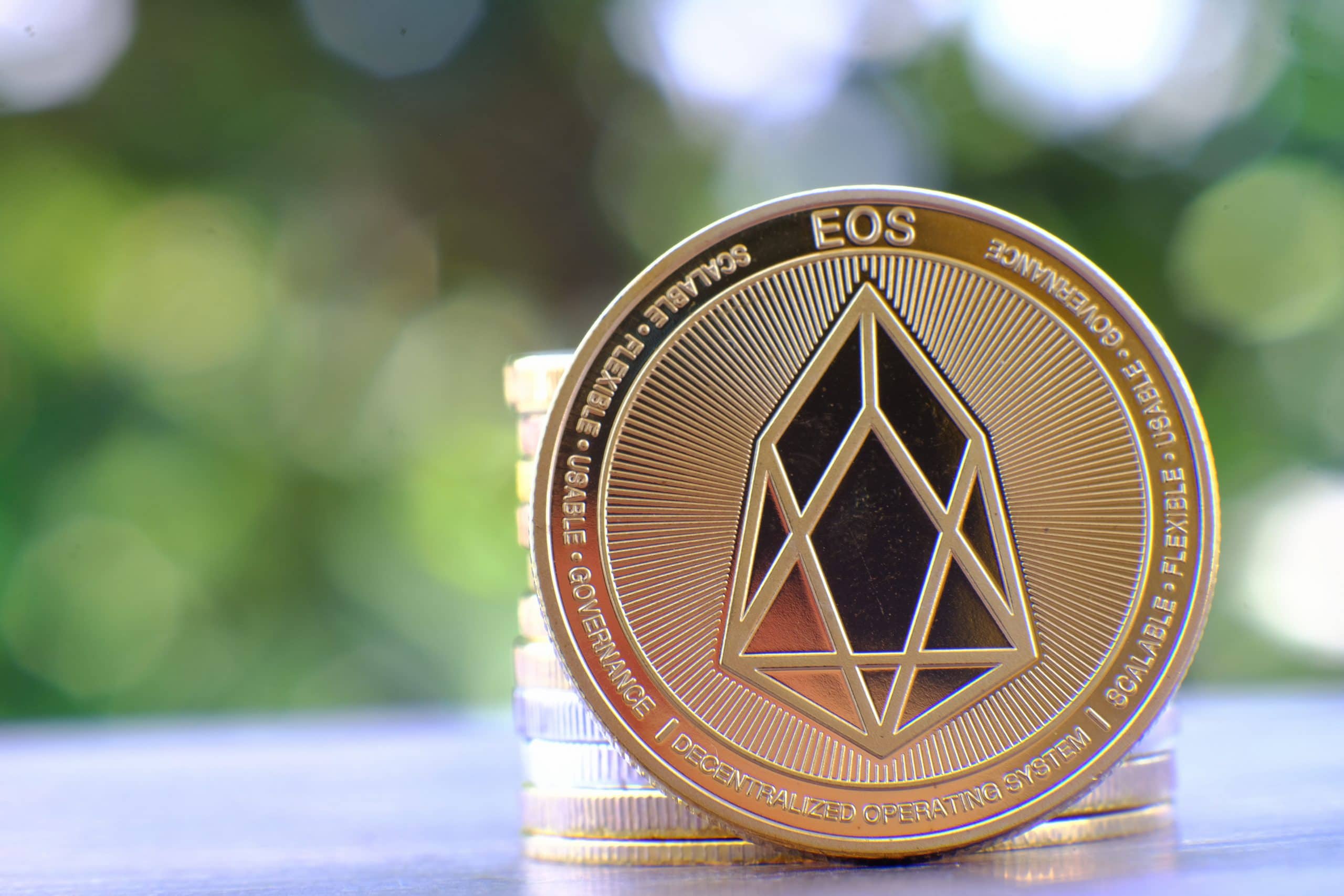Ein Bild von einer Münze der Kryptowährung EOS vor einem grünen Hintergrund