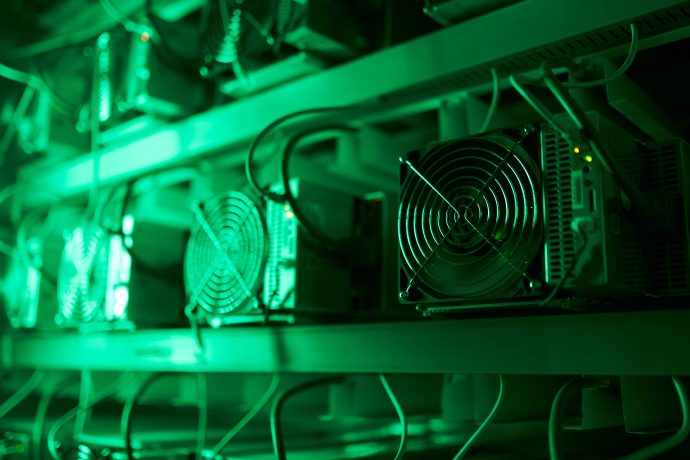 Reihen von BTC-Mining-Rigs mit Ventilatoren, beleuchtet mit grünem Licht, erzeugen in diesem Zentrum überschüssiger Energie ein faszinierendes Leuchten.