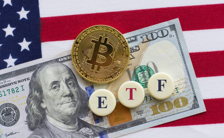 Eine Münze mit dem Bitcoin-Symbol, ein 100-Dollar-Schein und drei Kacheln mit der Aufschrift „ETF“ sind auf einer Fläche mit einer amerikanischen Flagge im Hintergrund angeordnet, was das steigende Interesse an Bitcoin-ETFs und ihre wachsenden Nettozuflüsse unterstreicht.