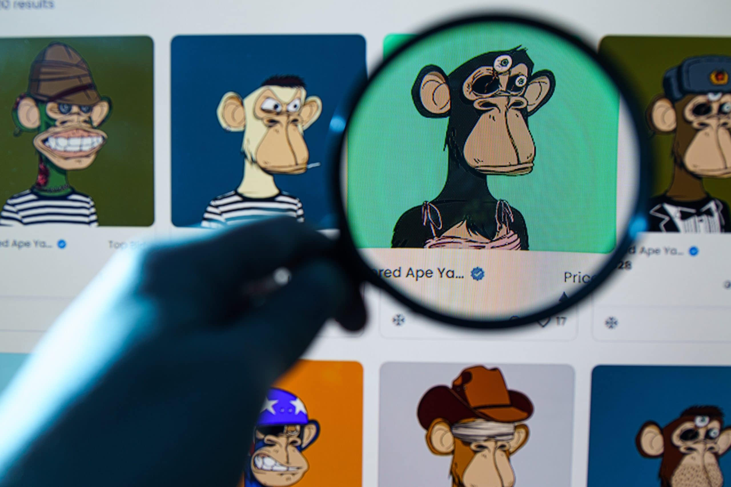 Eine Person hält eine Lupe über einen Computerbildschirm, auf dem eine Sammlung illustrierter Affenfiguren angezeigt wird, als würde sie einen automatisch gespeicherten Entwurf auf versteckte Details untersuchen.