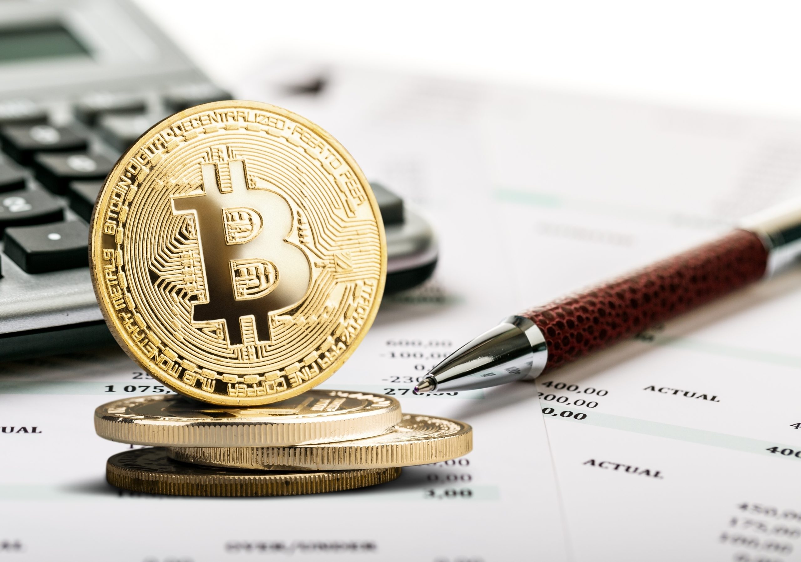Goldene Bitcoin-Münzen liegen auf Finanzdokumenten und deuten subtil auf Krypto-Trends und die Komplexität der Krypto-Besteuerung hin. Daneben warten Stift und Taschenrechner auf Entscheidungen, die von den BMF-Schreiben-Richtlinien beeinflusst werden.
