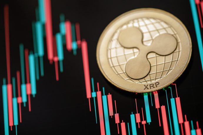 Eine goldene Ripple-Münze (XRP) ist vor einem Hintergrund aus roten und grünen Finanz-Candlestick-Charts platziert.