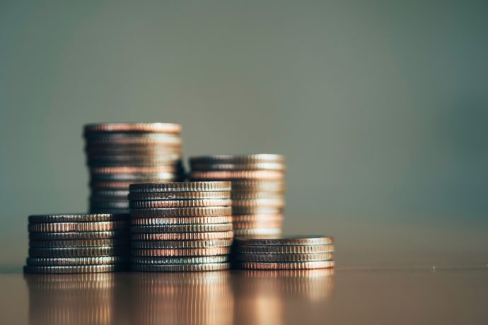 Münzstapel, die an den Anstieg der Stablecoin-Nutzer erinnern, sind in unterschiedlichen Höhen auf einer reflektierenden Oberfläche vor einem unscharfen Hintergrund angeordnet.