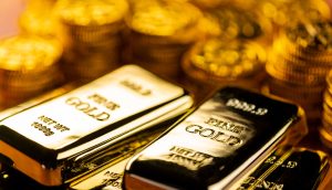 Verschiedene Goldbarren sind vor einem Haufen Goldmünzen zu sehen.