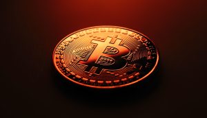 Eine leuchtende, orangefarbene Bitcoin-Münze zeigt stolz ihr markantes „B“-Symbol vor einem schattigen Hintergrund.