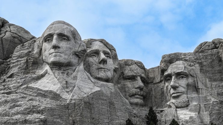 Das Mount Rushmore National Memorial zeigt die eingemeißelten Gesichter von US-Präsidenten vor dem Hintergrund eines bewölkten blauen Himmels.
