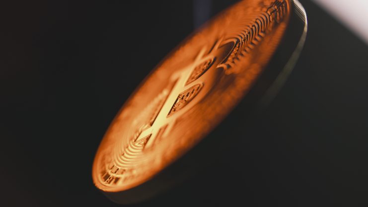 Nahaufnahme eines gekippten Bitcoins, das sein graviertes Design und seine glänzende Oberfläche vor einem dunklen Hintergrund hervorhebt und die komplexe Welt der On-Chain-Daten widerspiegelt.