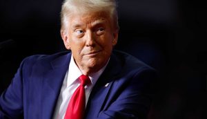 Der US-Präsident Donald Trump mit schelmischen Blick vor einem dunklen Hintergrund