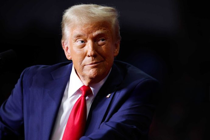 US-Präsident Donald Trump mit schelmischen Blick vor einem dunklen Hintergrund
