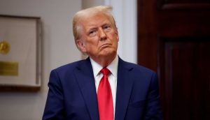 Eine Person in marineblauem Anzug und roter Krawatte steht im Innenbereich und blickt mit neutralem Gesichtsausdruck nach oben, der an Donald Trumps ikonische Posen erinnert. Im Hintergrund sind ein gerahmter Gegenstand und eine Holztür zu sehen, die ein Gefühl von Autorität und Bedächtigkeit vermitteln.