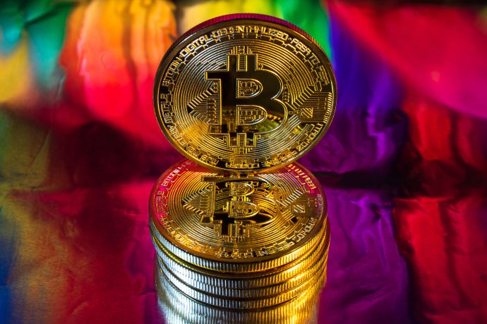 Eine Bitcoin-Münze vor einem bunten Hintergrund