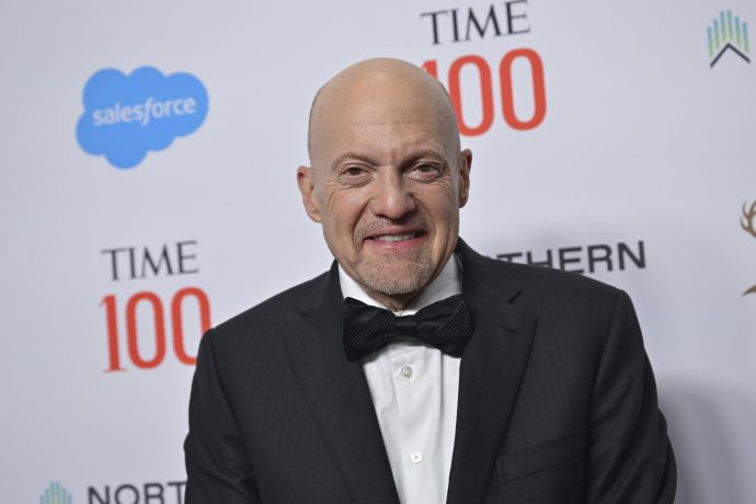 Jim Cramer im Smoking steht selbstbewusst vor einem Hintergrund, der mit Logos wie Time 100 und Salesforce geschmückt ist.