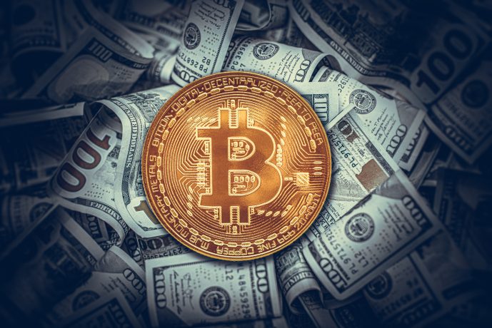 Eine goldene Bitcoin-Münze liegt auf einem Stapel verstreuter Hundert-Dollar-Scheine und symbolisiert im heutigen Krypto-Marktupdate die dynamische Beziehung zwischen Bitcoin und dem Dollar.