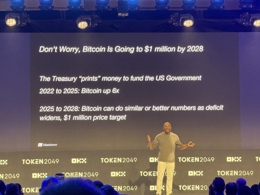 Ein Sprecher präsentiert auf der Veranstaltung TOKEN2049 eine Folie zu Bitcoin und prognostiziert, dass der Wert bis 2028 eine Million US-Dollar erreichen könnte. Außerdem skizziert er das potenzielle Preiswachstum von 2022 bis 2028 aufgrund der Politik des US-Finanzministeriums.