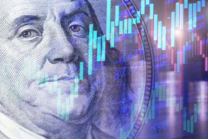 Nahaufnahme eines US-Hundert-Dollar-Scheins mit darüber gelegten Börsendiagrammen und Candlestick-Charts in Blau- und Lilatönen.