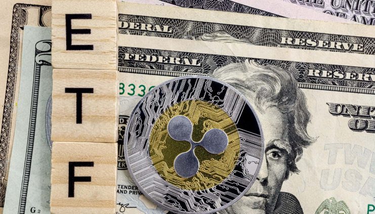 Eine Ripple-Kryptowährungsmünze liegt auf US-Dollarscheinen neben Holzfliesen mit dem Wort „ETF“, was auf das Potenzial für einen XRP-ETF in den USA hindeutet.