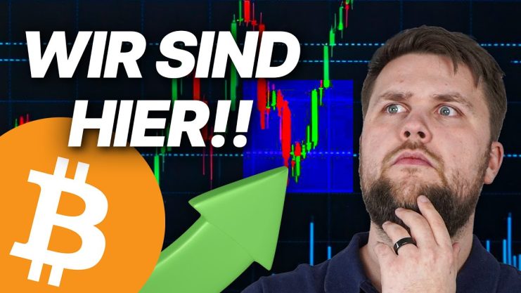 Eine Person sieht nachdenklich vor einem Bitcoin-Logo, einem grünen Aufwärtspfeil und einem Aktiendiagramm mit dem Text WIR SIND HIER!!, als ob sie überlegen, wie Bitcoin-Wale auf die aktuelle Marktlage reagieren.