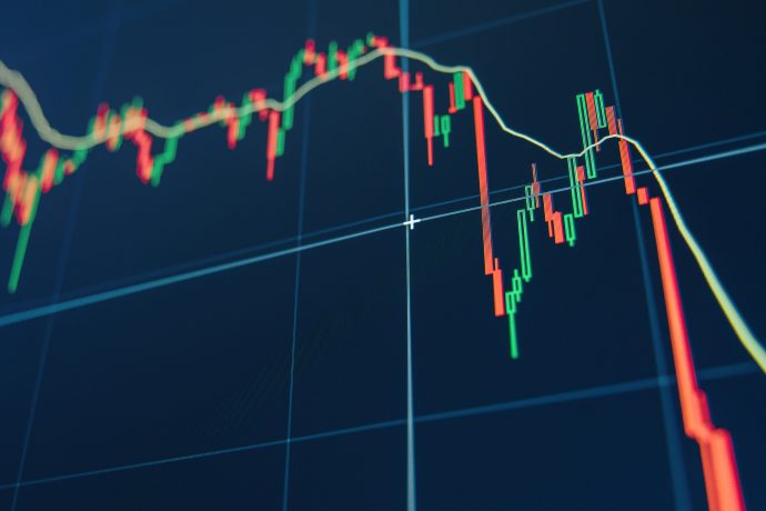 Ein digitales Diagramm mit roten und grünen Kerzen zeigt schwankende Finanzmarkttrends auf einem blauen Bildschirmhintergrund und spiegelt die volatile Welt der Kryptowährungen wider.