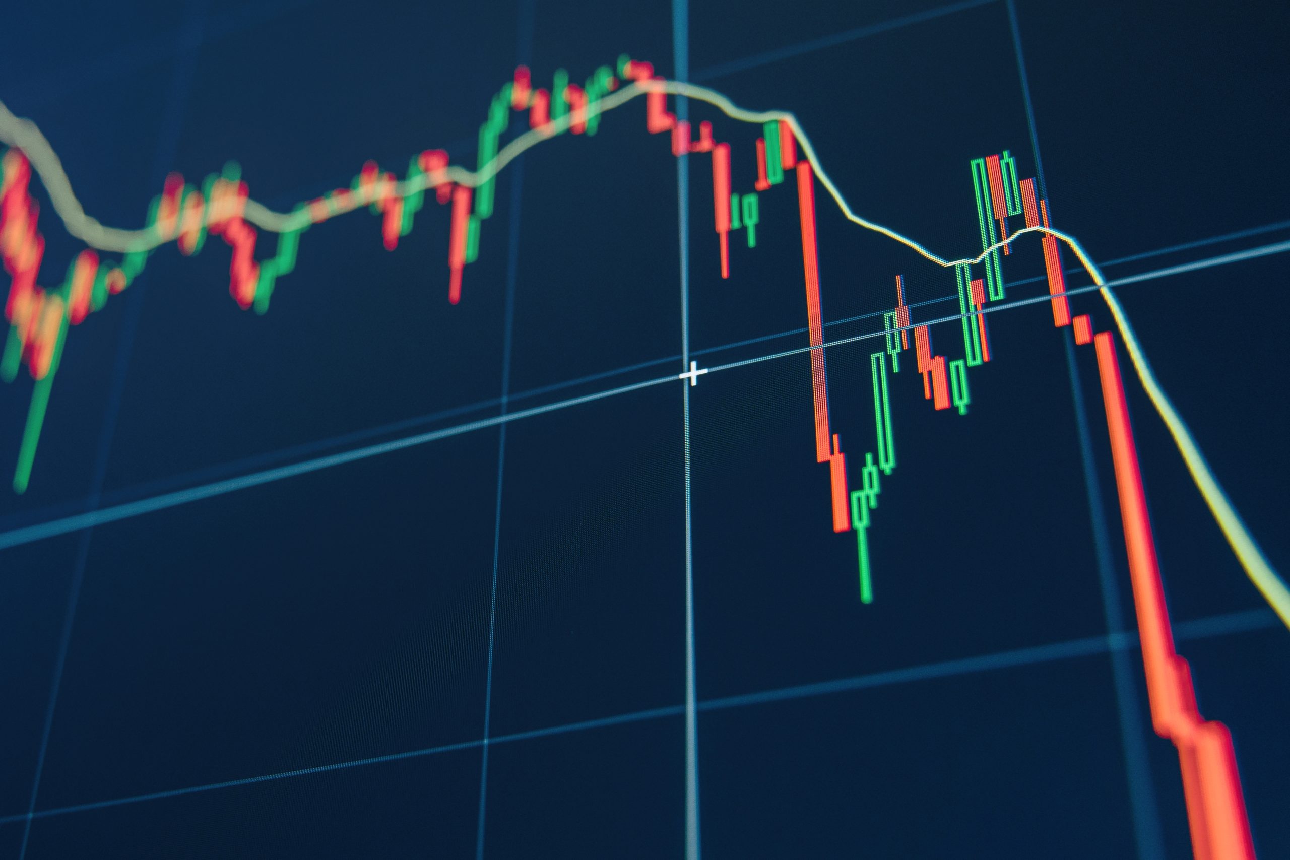 Ein digitales Diagramm mit roten und grünen Kerzen zeigt schwankende Finanzmarkttrends auf einem blauen Bildschirmhintergrund und spiegelt die volatile Welt der Kryptowährungen wider.