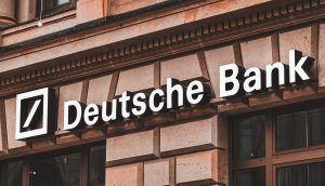 Logo und Name der Deutschen Bank an der Außenseite eines Steingebäudes mit großen Fenstern