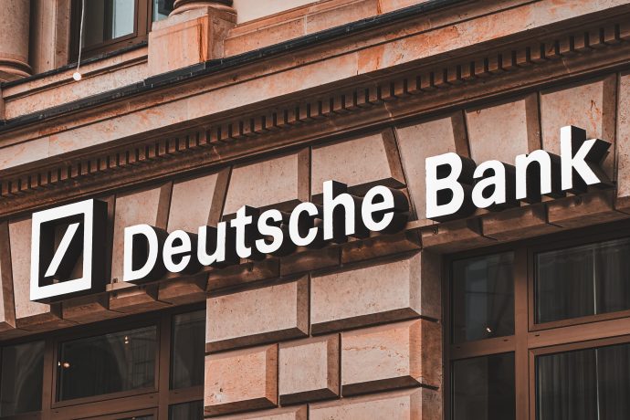 Logo und Name der Deutschen Bank an der Außenseite eines Steingebäudes mit großen Fenstern