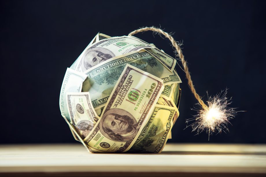 Ein in US-Hundertdollarscheine eingewickelter Ball mit einer angezündeten Lunte, die einer Zeitbombe ähnelt, wird auf einer hölzernen Oberfläche vor einem dunklen Hintergrund platziert und symbolisiert den explosiven Aufstieg des Krypto-Reichtums.
